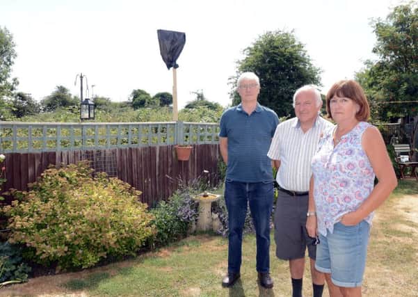 Brian and Paula Darling, right with their neighbour Ian Ledger by the post they erected to illustrate the height of the proposed fence. Picture: Kate Shemilt