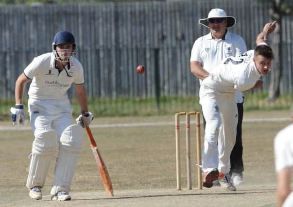 Worthing bowler Martyn Swift puts down a delivery as Slinfold's Sean Overton watches on. Picture by Stephen Goodger
