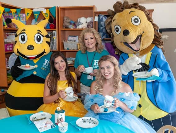 St Barnabas House shop manager, Michelle Shephard-Ede, enjoys a cup of tea with the St Barnabas House mascot Barnabee, Littlehampton's very own Hampton The Hedgehog and two Princesses from A Star Parties & Events