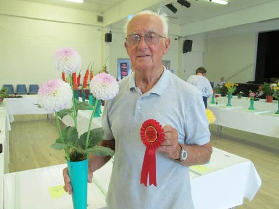 Ted Banks with the red rosette he won for best flower in show with his dahlias. Pictures: Barry Hillman