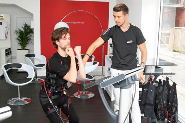 DM1881778a.jpg Worthing Herald reporter James Butler tries out Bodystreet in Worthing ahead of its opening, - a gym where you put on a bodysuit which gives your muscles electric shocks while you're working out. With manager Charlie Mathe. Photo by Derek Martin Photography. SUS-180817-202915008