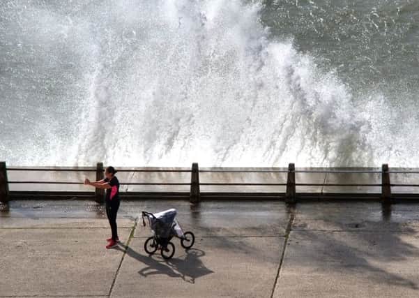 The woman taking pictures in Newhaven where waves were crashing against the sea wall