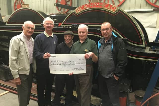 Sussex Vintage Model Railway representatives hand over their cheque to David Jones, (second from the right) project secretary and treasurer. From left to right they are Philip Cooke, Chairman, David Reed, Treasurer, member Tony Funnell who is also  working on the project, and Peter Bryant, Deputy Chairman. A 1930s Hornby loco stands on Beachy Heads running plate. SUS-180925-104646001