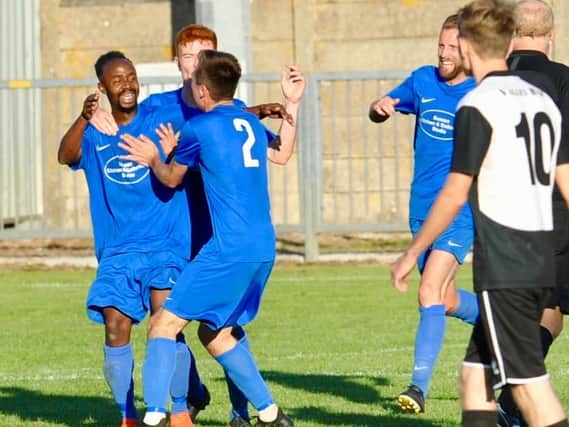 Martin Mutungi is mobbed by his Shoreham team-mates after netting the winner against East Preston. Picture by Stephen Goodger