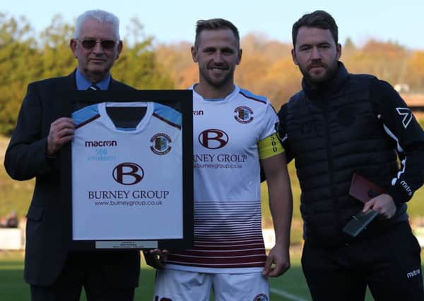 Hastings United Football Club captain Sam Adams receives a framed shirt from president Dave Ormerod (left) and manager Chris Agutter (right) in recognition of his 500 appearances for the club. Picture courtesy Scott White