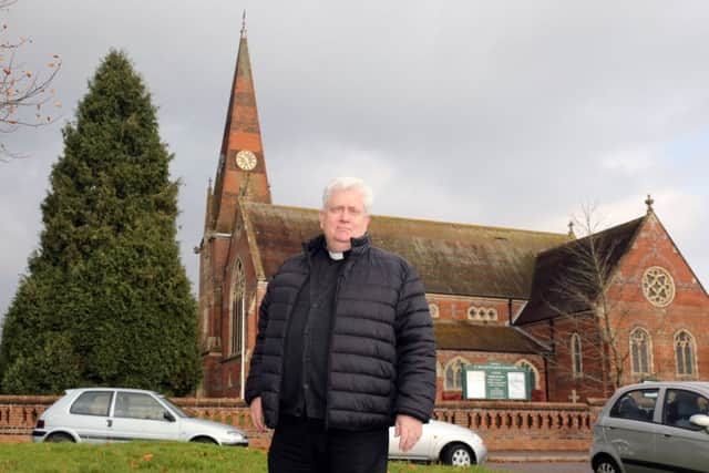 Father Kevin O'Brien outside St John's Church in Burgess Hill which shows the giant Christmas tree