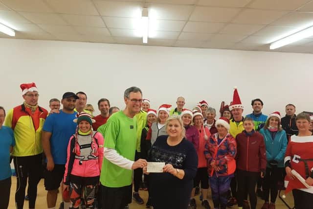 Ian Reader, vice-chairman of the Arunners, presents the Â£1,000 cheque to Teresa Cash from Littlehampton and District Foodbank, before the group set off on a  Christmas lights run