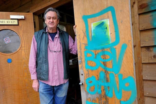 Bobby Schuck next to the Bev Gang graffiti tag left after the break-in. Photo by Steve Robards