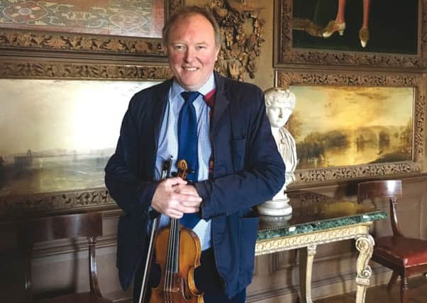 Sussex creative Andrew Bernardi with his Stradivarius violin beneath the Grinling Gibbons carved instruments at Petworth House which were both created c.1696. SUS-190128-113850001