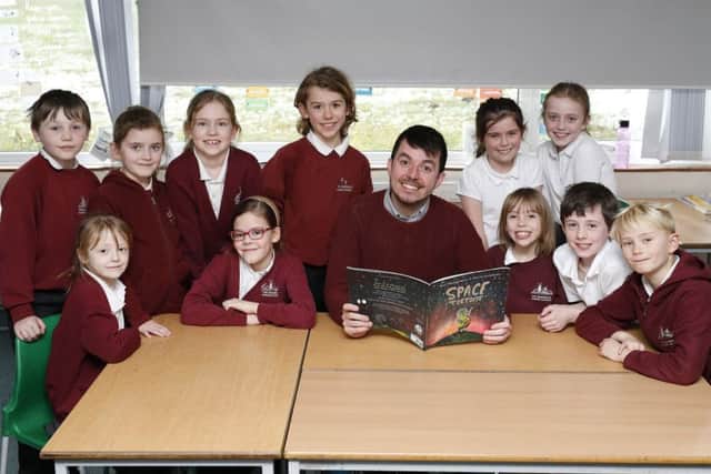 Ross Montgomery with some of the pupils with his new book