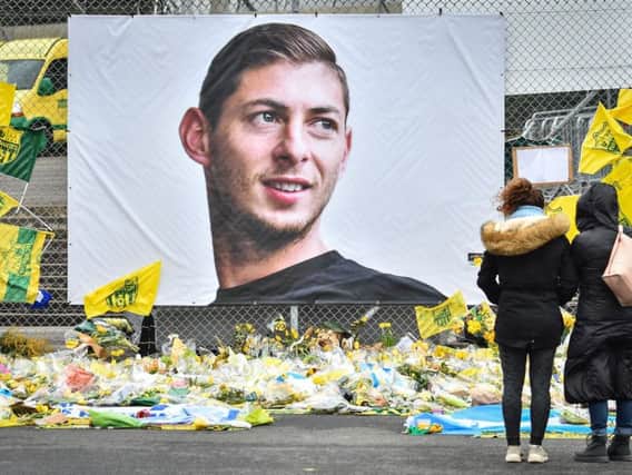 People look at yellow flowers displayed in front of the portrait of Argentinian forward Emiliano Sala at the Beaujoire stadium in Nantes (Picture by LOIC VENANCE/AFP/Getty Images)