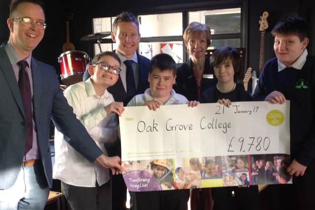Richard Hopton, general manager at Hilton Avisford Park, and Philippa Redwood, his PA and a foundation champion, presenting the grant to staff and pupils at Oak Grove College