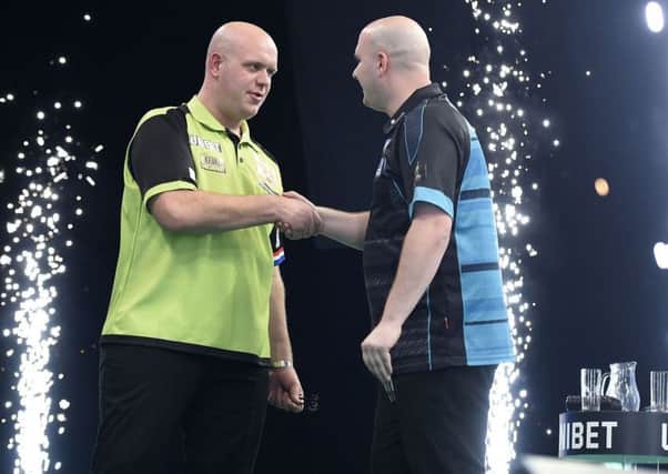Rob Cross (right) shakes hands with opponent Michael van Gerwen at the 3Arena in Dublin tonight. Picture courtesy Michael Cooper/PDC