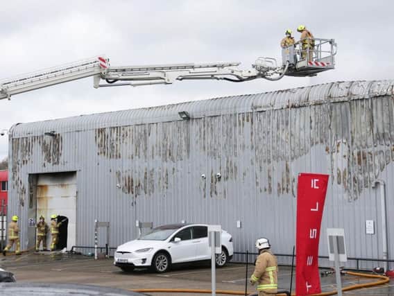 Fire crews control the fire at the Tesla dealership