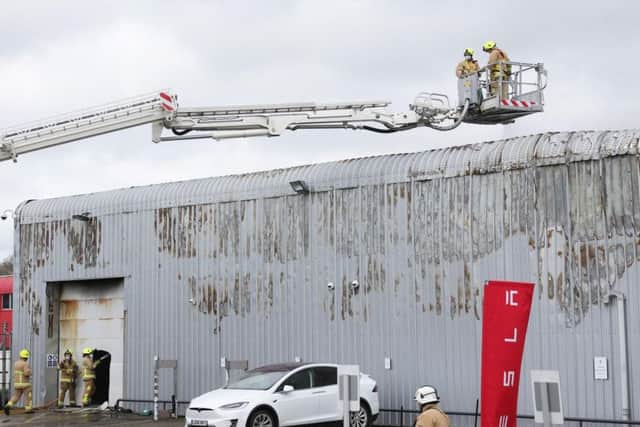 Fire crews control the fire at the Tesla dealership