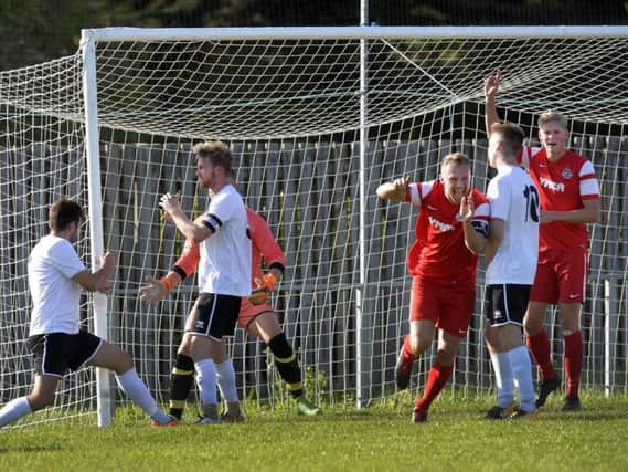 Tom Gilbert (centre, red) and Dean Bown celebrate against Eastbourne United. Picture by Jon Rigby.