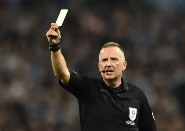 Referee Jonathan Moss shows a yellow card to a player during the English League Cup final football match between Manchester City and Chelsea at Wembley stadium in north London on February 24, 2019. (Photo by Glyn KIRK / AFP) / RESTRICTED TO EDITORIAL USE. No use with unauthorized audio, video, data, fixture lists, club/league logos or 'live' services. Online in-match use limited to 75 images, no video emulation. No use in betting, games or single club/league/player publications. /         (Photo credit should read GLYN KIRK/AFP/Getty Images) 775299801