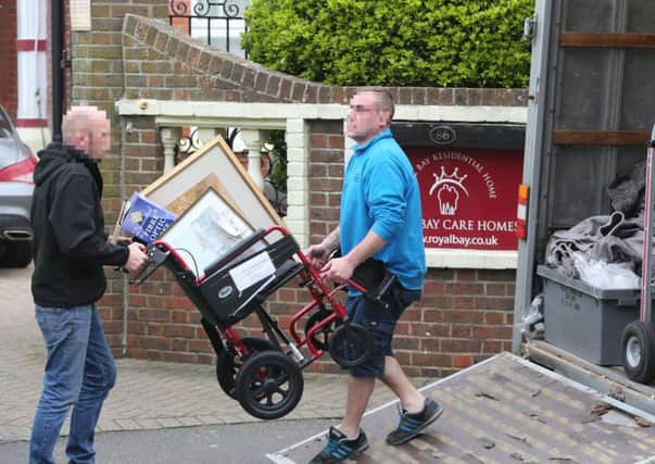 Two men removing a wheelchair and other belongings from the care home.