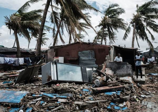 An owner (2nd R) stays at his destroyed bar after the cyclon Idai hit near the beach in Beira, Mozambique, on March 23, 2019. - The death toll in Mozambique on March 23, 2019 climbed to 417 after a cyclone pummelled swathes of the southern African country, flooding thousands of square kilometres, as the UN stepped up calls for more help for survivors. Cyclone Idai smashed into the coast of central Mozambique last week, unleashing hurricane-force winds and rains that flooded the hinterland and drenched eastern Zimbabwe leaving a trail of destruction. (Photo by Yasuyoshi CHIBA / AFP)        (Photo credit should read YASUYOSHI CHIBA/AFP/Getty Images) SUS-190104-114605003