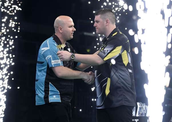 Rob Cross (left) shakes hands with beaten opponent Daryl Gurney at the end of their match in Belfast tonight. Picture courtesy Michael Cooper/PDC