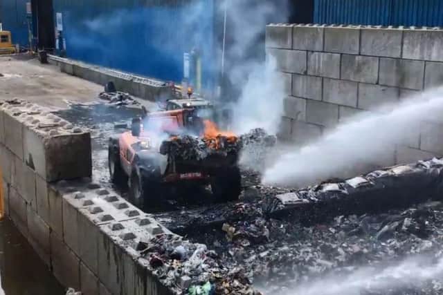 A digger takes fiery waste from the building.