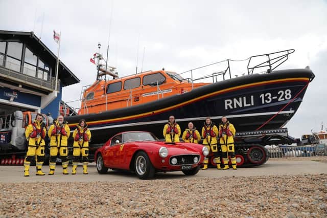 The red Ferrari pictured in front of the lifeboat it funded, alongside Hastings RNLI crew members. Photo by Kt Bruce. SUS-190423-122200001