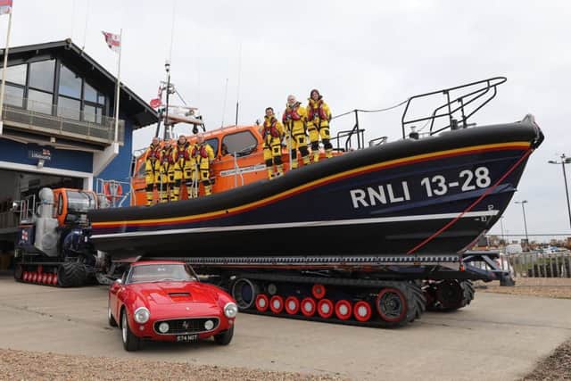 The red Ferrari pictured in front of the lifeboat it funded, alongside Hastings RNLI crew members. Photo by Kt Bruce. SUS-190423-122223001