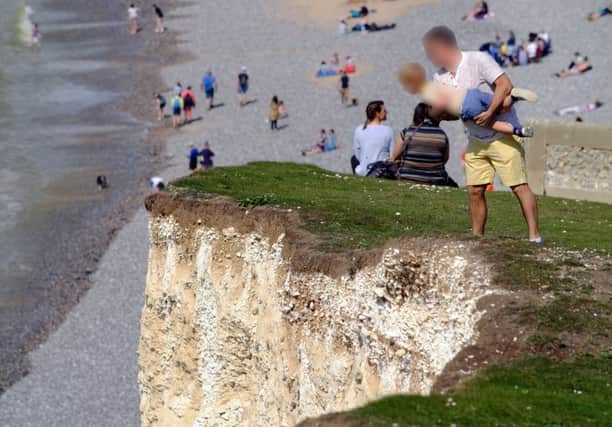 The man held his son over the steep cliff edge. Photograph by Peter Cripps