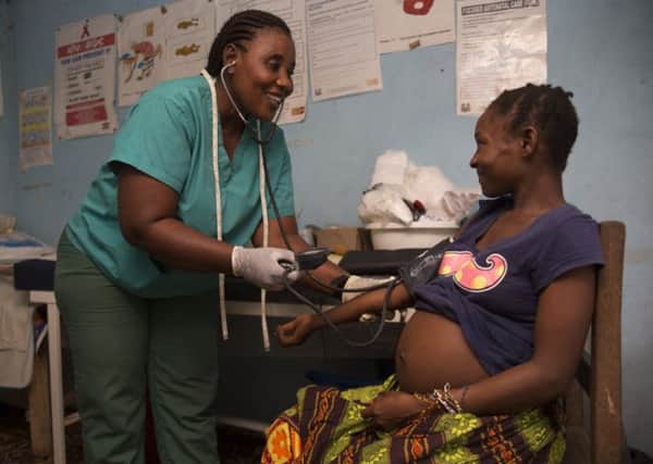 Heavily pregnant Jebbeh Konneh is checked by Nurse Judith in a temporary clinic in Sawula village, Sierra Leone. This clinic, which receives support from Christian Aid, has no electricity and only two delivery beds.