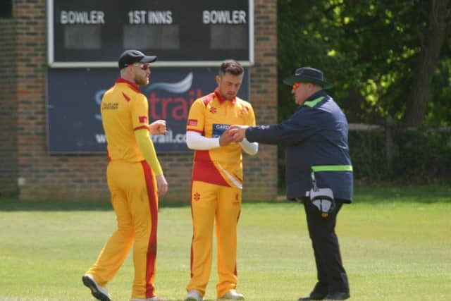Tom Haines (centre) and captain Michael Thornely (left) exchange views with umpire about condition of match ball