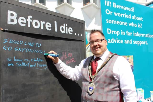 Billy Blanchard-Cooper writing on the Before I die... board during Dying Matters Week