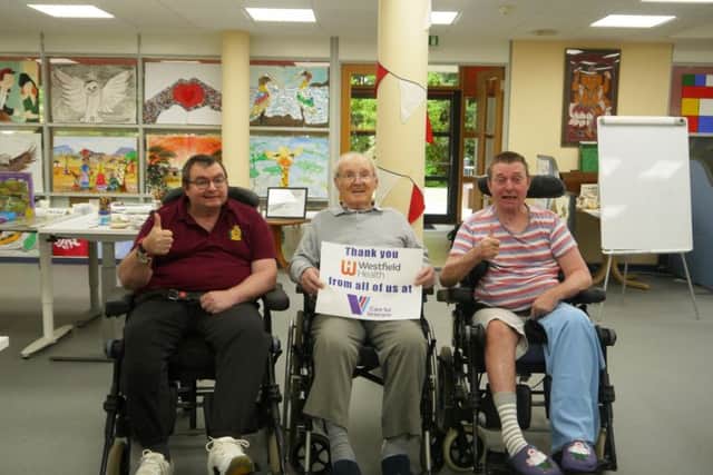 Care for Veterans residents holding a thank you sign in the social and recreation room