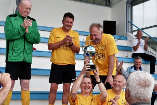 Margaret Blurton, captain of the the Old Bexhillians walking football tournament team, holds the trophy aloft