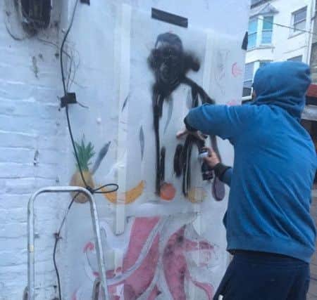 Graffiti artist Horace painting the mural of Kenny Tutt in Warwick Street, Worthing