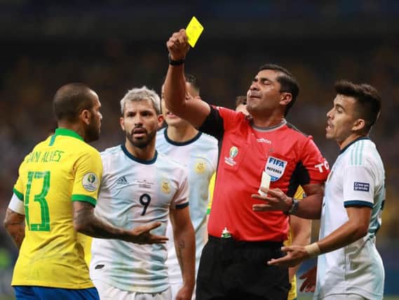 Referee Rody Zambrano books Dani Alves as Argentina's Sergio Aguero watches on. Picture courtesy of Getty Images