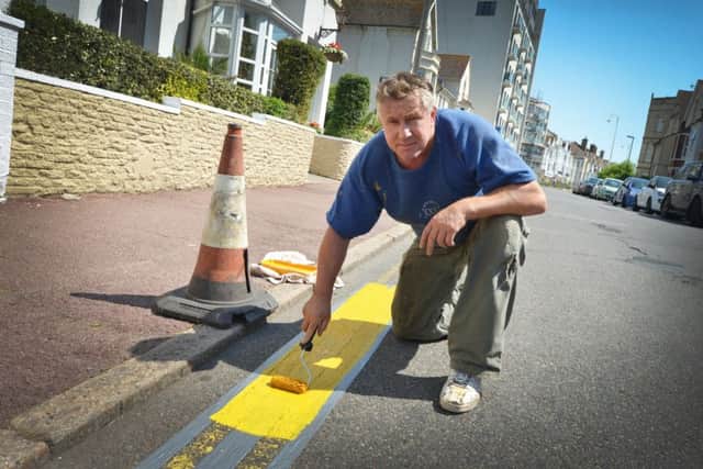 Tony Cunningham painting double yellow lines outside his guest house, Park Lodge, in Bexhill. SUS-190723-121332001