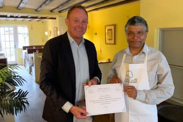 Nick Herbert MP presenting owner Sanjay Jha with the certificate and Tiffin Cup apron