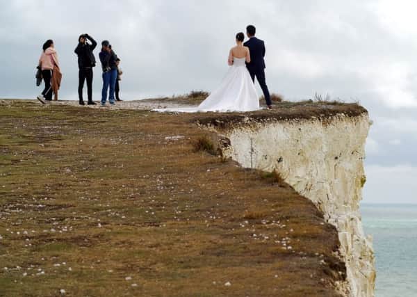 Newlyweds posing for photographs on the edge of Birling Gap cliffs. Photo by Peter Cripps