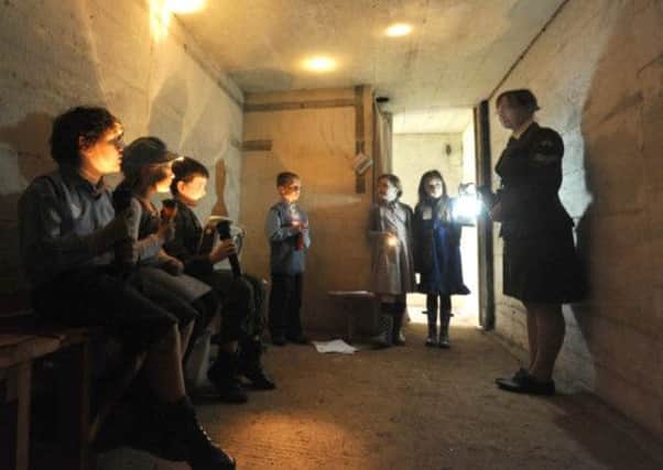 Schoolchildren experience the dank gloom of an air raid shelter