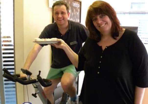 Littlehampton Barclays bank manager Gary Nealgrove pedals away on an exercise bike, while colleague Tanya Gibbins tempts him with a cake during a charity event at the branch in aid of the Christie Hospital