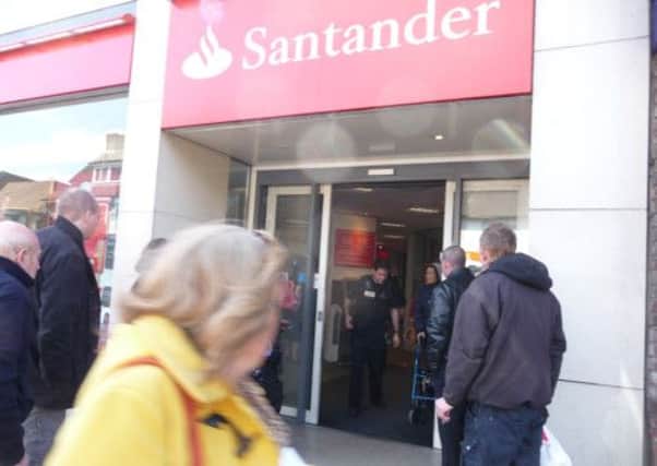 Police emerge from the Santander branch as shoppers look on.