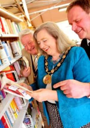 JPMT 090413 Opening of Lions Club charity book shop at South Downs Nursery by the Chairman of Mid Sussex District Council, Councillor Mrs Mandy Thomas-Atkin, pictured choosing a book with Burgess Hill District Lions Club president John Gee left and nursery manager Mark Hillyard.