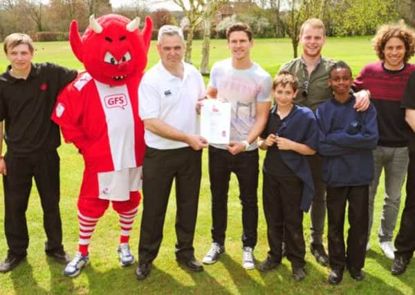 JPCT 290413 Crawley footballers visiting Muntham House School. Richard Bell, head of care receives the Junior Reds Partnership Agreement certificate from Josh Simpson with other players Mark Connolly left and Sergio Torres and pupils. Photo by Derek Martin