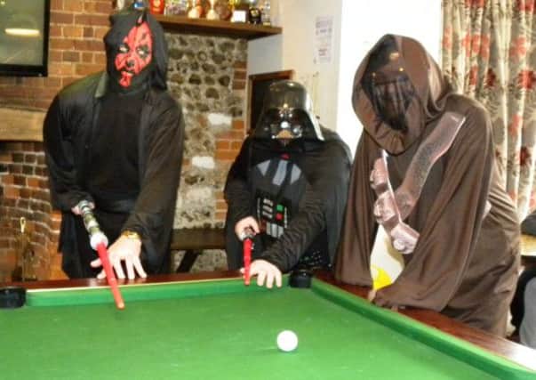 Richard Milburn (left) as Darth Maul and Jeff Roddis (centre) as Darth Vader, prepare to do battle on the pool table, watched by Dan Wood, as a Jawa, at the start of their pool marathon