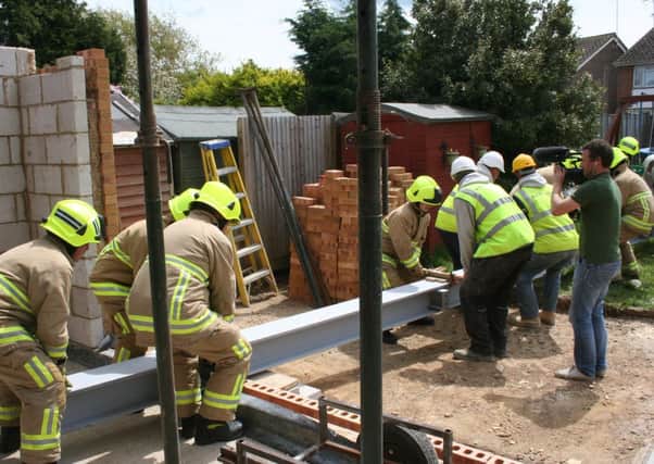Firefighters lending a hand to building in moving a 700kg steel support as part of the redesign of disabled East Preston seven-year-old, Iona-May Thorne's home redesign. PHOTO: Eddie Mitchell