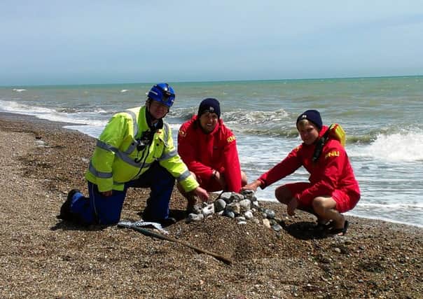 Coastguard Laurence Pettitt and lifeguards Arran Barker and Joshua O'Connort-Wright bury the suspect cylinder under a mound of stones