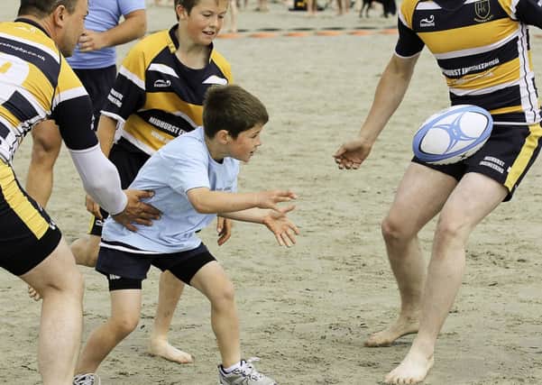 At the Chichester Beach Rugby tournament at West Wittering, a young Team Avenger player (blue) tries to find a way through the Midhurst team  Picture by Chris Hatton