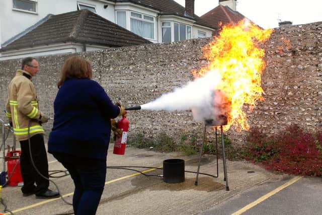 Firefighter Gavin Ross shows the Herald & Gazettes Shirley Coller how to put out the flames