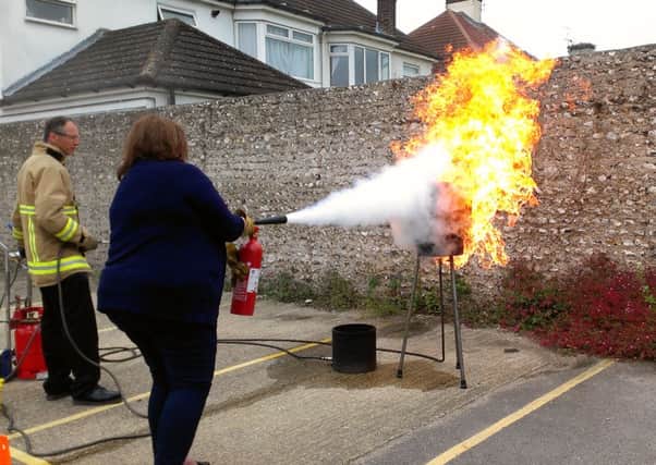 Firefighter Gavin Ross shows the Herald & Gazettes Shirley Coller how to put out the flames