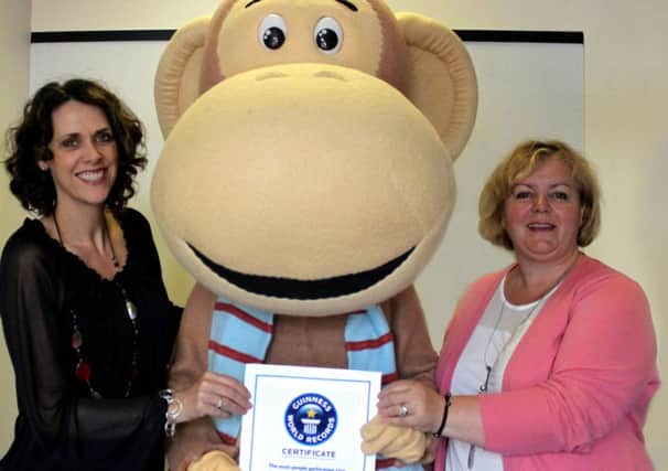 Marketing & communications manager at SignHealth, Gail Bunn, Olli the monkey and events & corporate Fundraiser at SignHealth, Linda Petrons, with the certificate from Guinness World Records